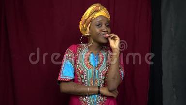 一位穿着非洲传统服装的开朗的黑人妇女，双手紧握嘴唇，双手伤痕累累